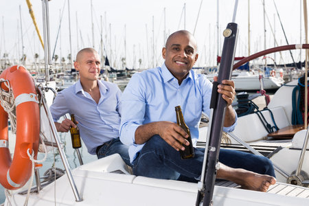 Two men in blue shirts relaxing on sailing yacht in the portの写真素材