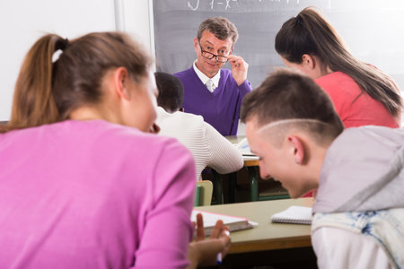 Professor watching as student write off on examsの写真素材