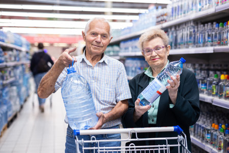 Mature european spouses selects bottled water in the department of supermarketの写真素材