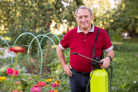 Male farmer spraying his garden with insecticides from spray bottle