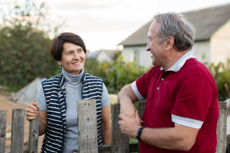Elderly couple standing together near wooden fence in gardenの写真素材