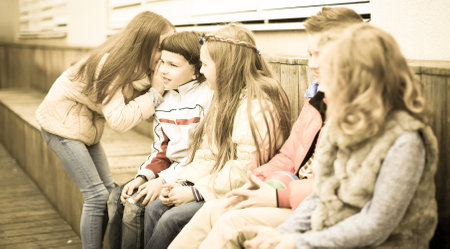 Children on a bench playing Chinese whispersの写真素材