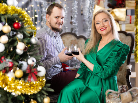 Husband and wife with glasses of red wine celebrate Christmas