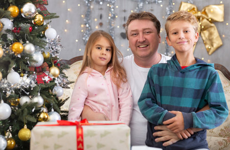 Dad with son and daughter on sofa in Christmas interior