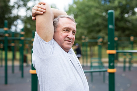 Stretching and active senior man at park for training, exercise and cardio wellness. Fitness, arm stretchの写真素材