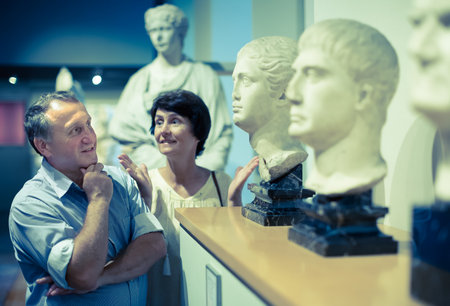 Mature couple turists examines the exhibit in museum