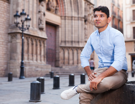 Young guy in blue shirt sitting in cityの写真素材