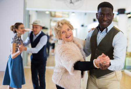 Man and senior woman dancing waltz in studioの写真素材