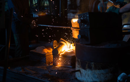 Pouring molten metal into a sand mold in the foundry shop of metallurgical plantの写真素材