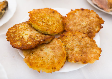 Fried grated potato pancakes with sour cream on white plate