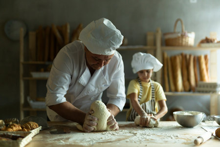 Daughter and father make dough together in the bakery kitchenの写真素材