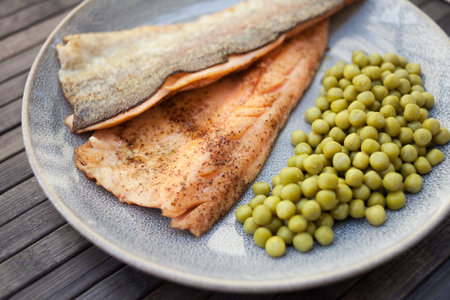 Fried trout fillets served with green peasの写真素材