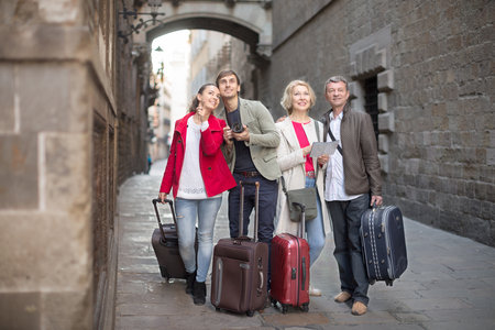 Tourists with suitcases and camera walk along the historic streets of European cityの写真素材