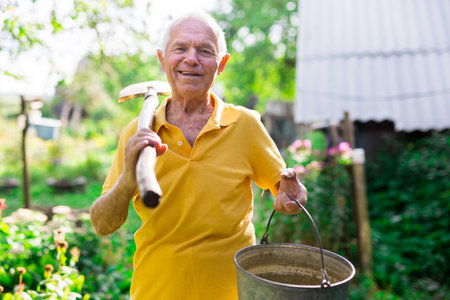 Portrait of mature farmer with shovel on gardenの写真素材