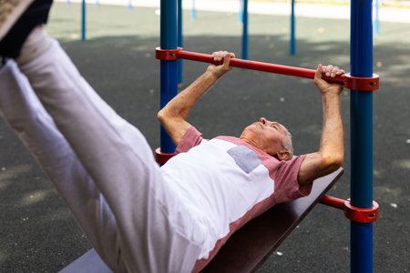 Open air gym. Street training on the municipal sports equipment. Elderly man pumps the press in city...
