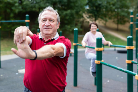 Elderly man doing gymnastics on an outdoor sports ground