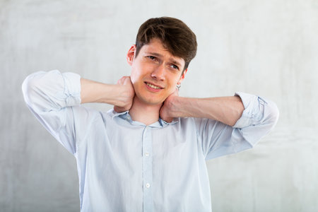 Young guy holding his sore neckの写真素材