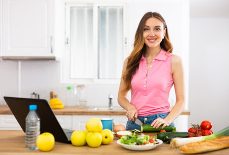 Woman cooking salad recipe from the Internetの写真素材