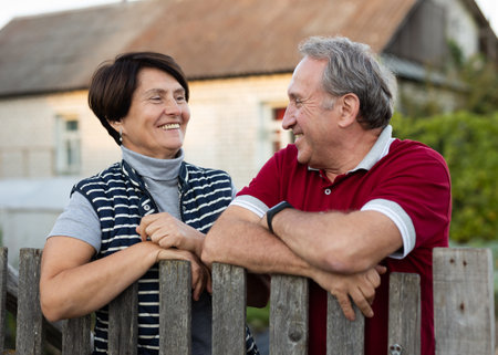 Elderly couple standing together near wooden fence in gardenの写真素材
