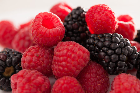 Handful of raspberry and blackberry berries on white backgroundの写真素材