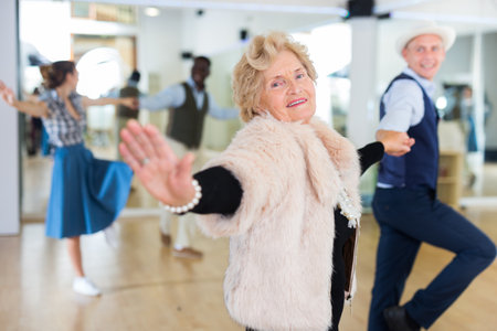 Senior woman and younger man dancing swing in studioの写真素材