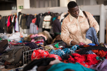 Man looks at second-hand clothes at a flea market