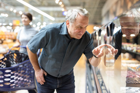 Man chooses cakes at showcase of confectionery departmentの写真素材