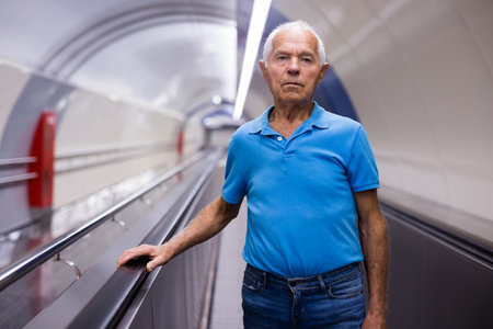 Elderly man standing on moving walkwayの写真素材
