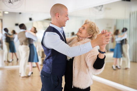 Man and senior woman dancing waltz in studioの写真素材