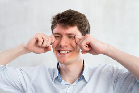 Portrait of young guy with itchy eyes in studioの写真素材