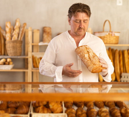 Man customer holding loaf of bread and baguettes with hands in disposable gloves.の写真素材