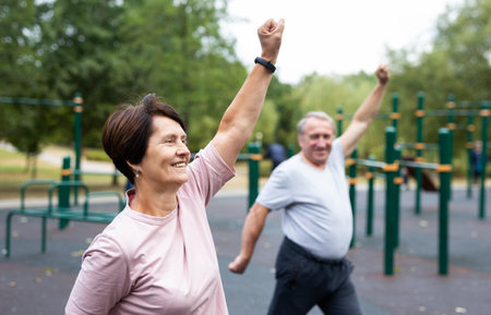 Elderly man and woman doing gymnastics on outdoor sports groundの写真素材