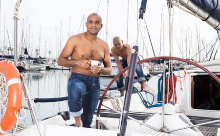 Sailor in jeans resting on a yacht in the port in the morningの写真素材