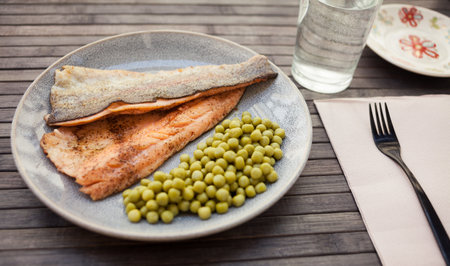 Fried trout fillets served with green peasの写真素材