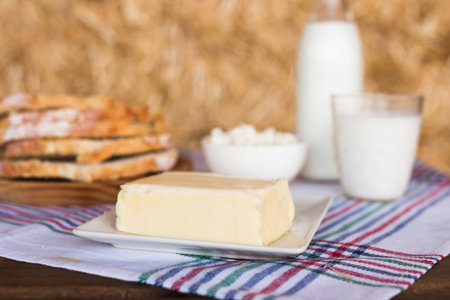 Butter, dairy products and bread on the table against the background of hayの写真素材