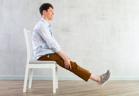 Young guy doing exercises on chairの写真素材