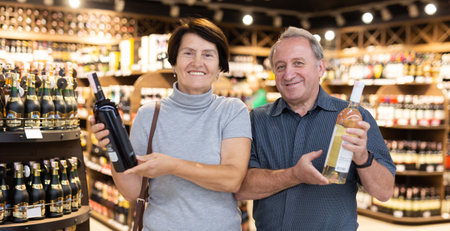 Mature couple choosing nice bottle of wine in supermarketの写真素材