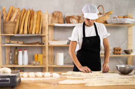 Elderly woman baker rolls out doughの写真素材