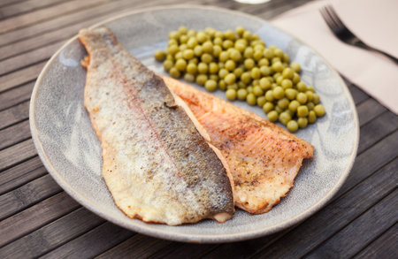 Top view of baked trout fillet served on plate with peas closeupの写真素材