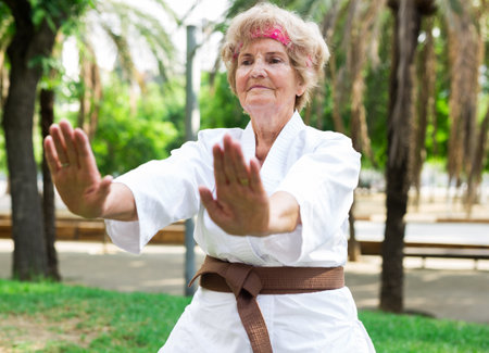 Mature lady in karate suit exercising outdoorsの写真素材