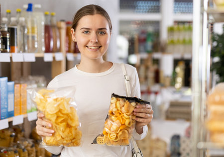 Female shopper selects tasty potato chips in supermarketの写真素材