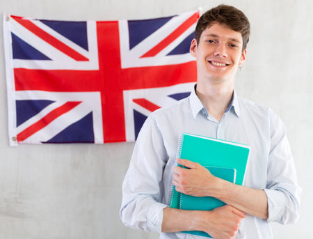 Male student with notebooks in his hands against background of the UK flag. Concept of studying abroad and immigrationの写真素材