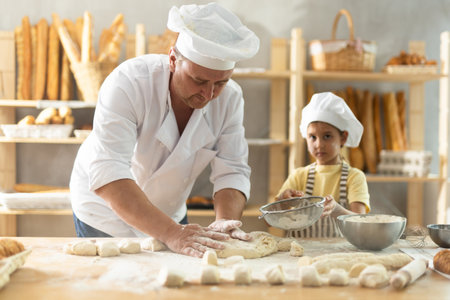Father and daughter roll out dough together to make delicious breadの写真素材