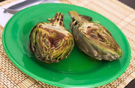 Cooked fried halves artichokes on green plateの写真素材