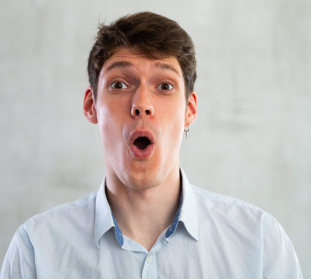 Portrait of young surprised guy in studioの写真素材