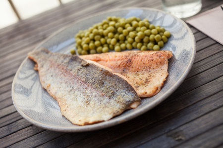 Delicious baked trout fillet with green peasの写真素材