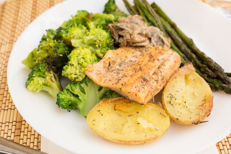Delicious dish of fried river trout fillet with garnish of broccoli, asparagus sprouts, baked potatoes and mushroom sauceの写真素材