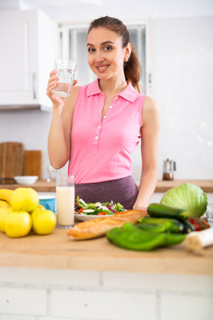 Young attractive woman drinking water at homeの写真素材