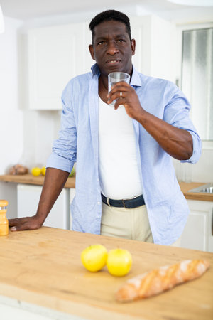 Man holding glass, drinking water at homeの写真素材