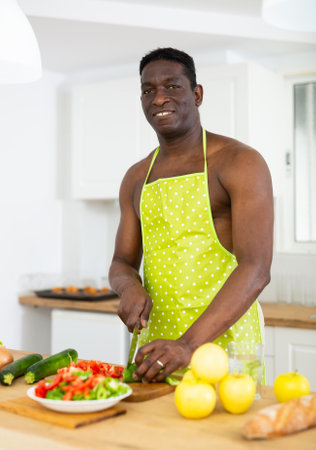 Man in apron making dinner at kitchen tableの写真素材
